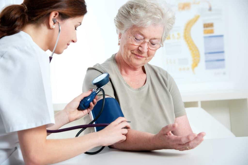Young Nurse Taking Blood Pressure of An Old Woman